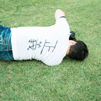 芝生に横たわる正義マンの後ろ姿、背中に文字入りの写真