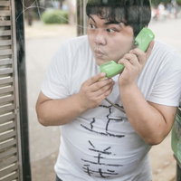 もしもし、おまわりさん、通報したいんですが...と緑の電話ボックスで話す男性の写真