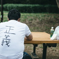 公園のベンチでイートインする正義マンの後ろ姿の写真