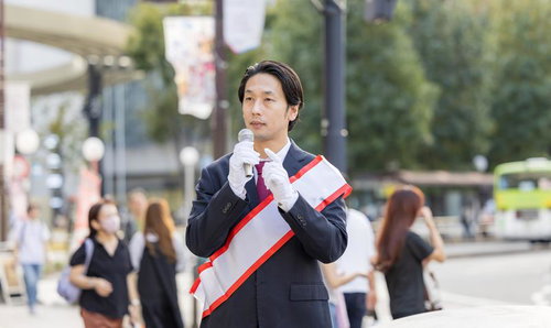 マイクを握り、真剣な眼差しで語りかける若手政治家の街頭演説