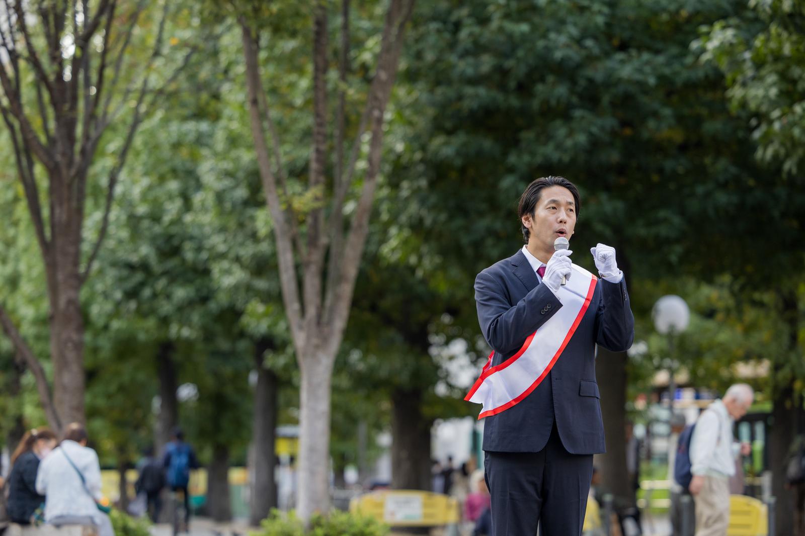 公園で街頭演説をするたすきを掛けた男性［モデル：大川竜弥］