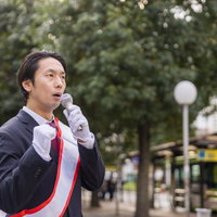 熱意を込めた街頭演説をするスーツ姿の男性の写真