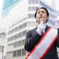 上を見上げながらマイクを握る立候補者の男性の写真