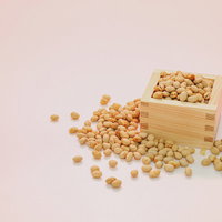 木製の枡から溢れ出る節分豆と大豆の豆まきの写真