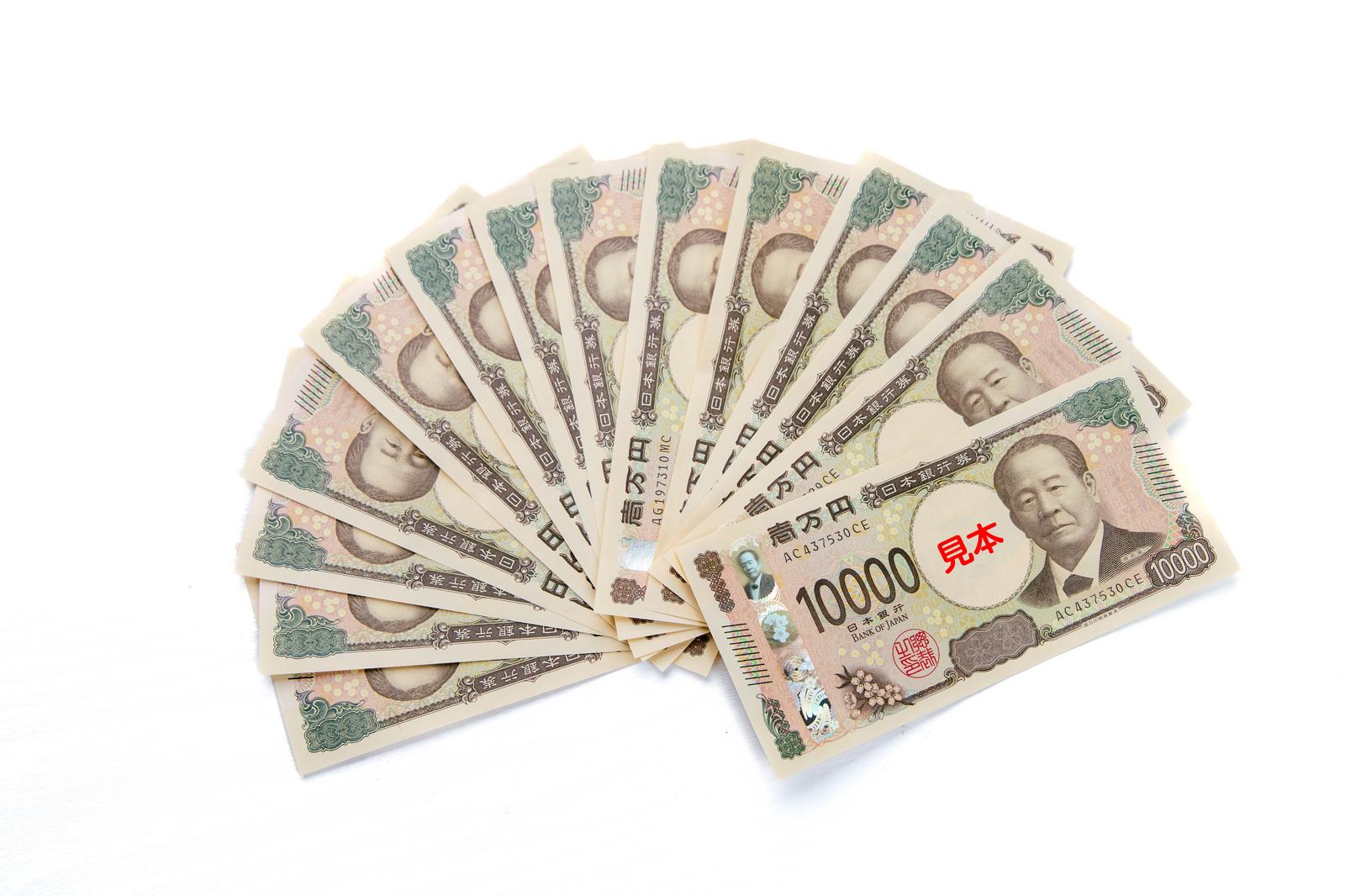 複数枚の一万円札を扇状に広げ、手前に見本札が置かれている
