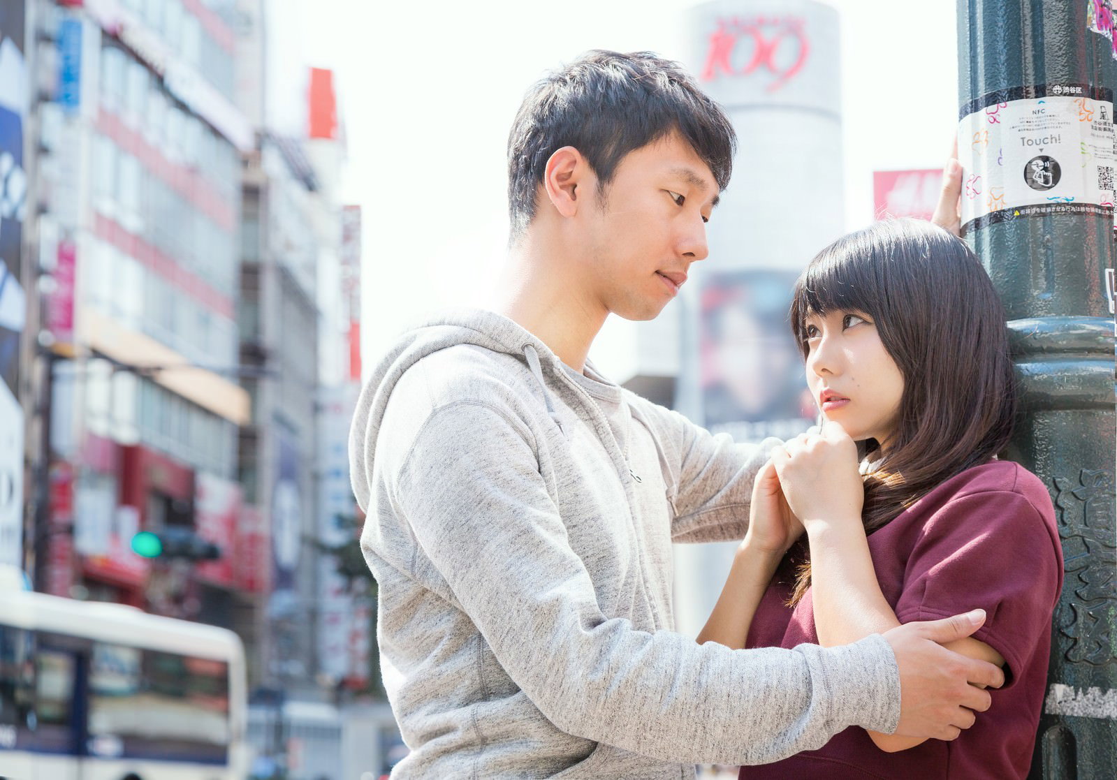渋谷スクランブル交差点で寄り添うカップル。グレーのパーカー男性と紫色トップスの女性が向き合う［モデル：大川竜弥 Lala］