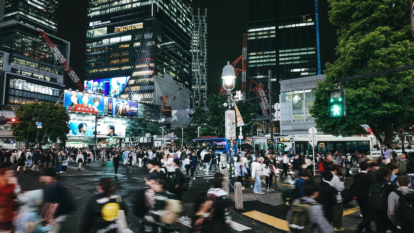 夜間の渋谷スクランブル交差点で青信号に多くの人が横断する様子