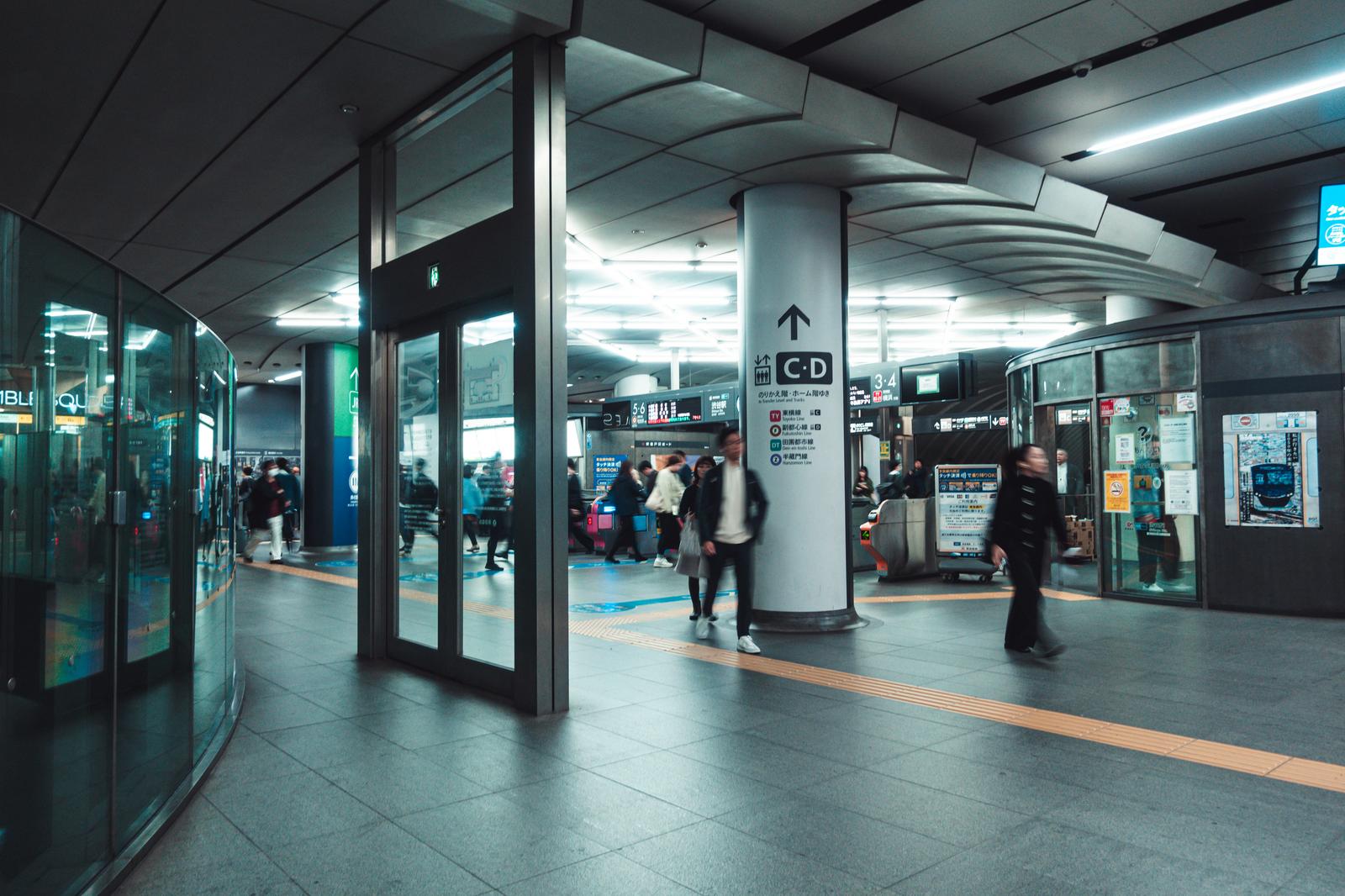 渋谷駅の地下通路を移動する人々の群れと案内柱