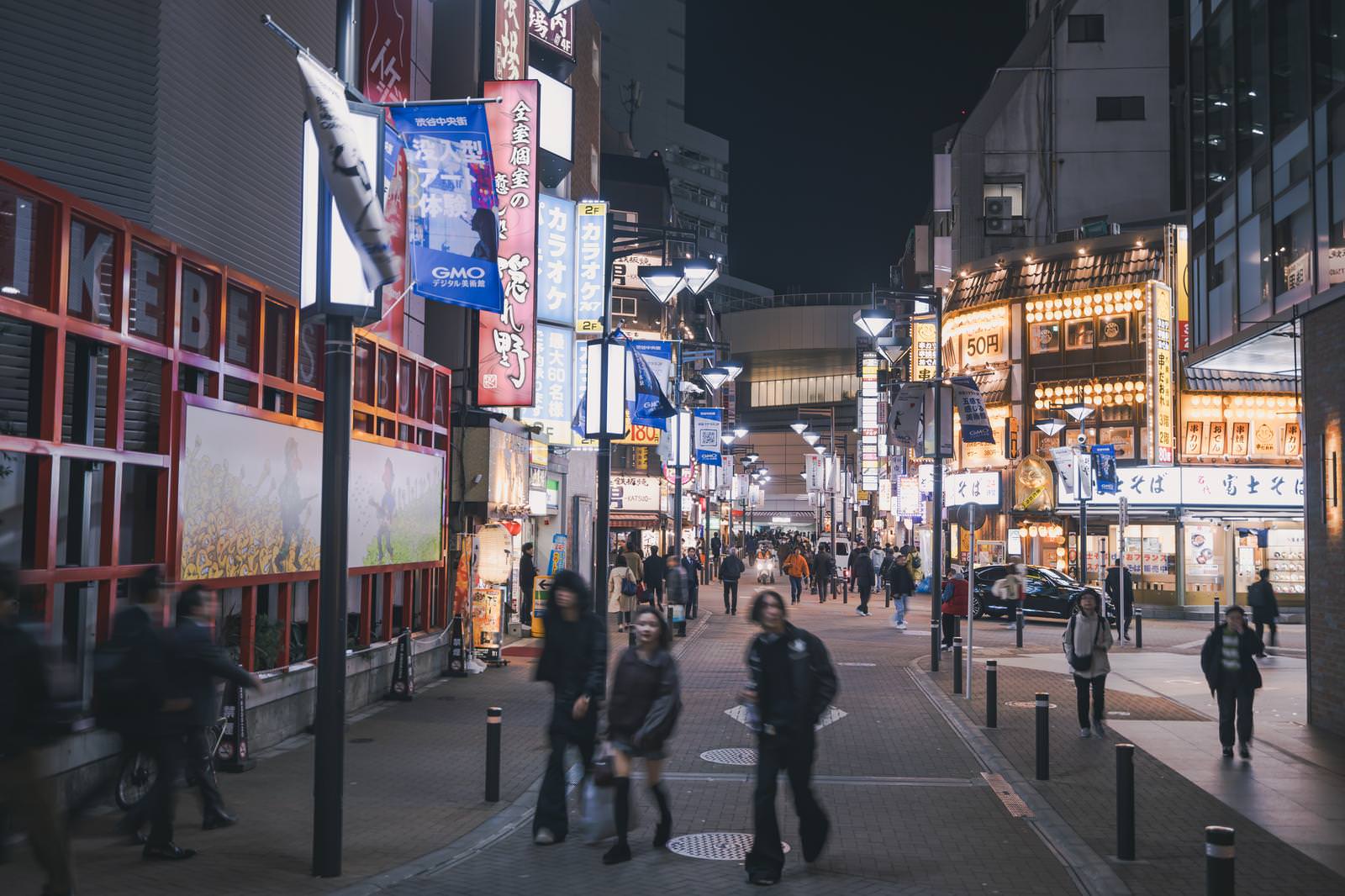 夜の渋谷セルリアンタワー通りで、ネオン看板が灯る飲み屋街を多くの人が行き交う