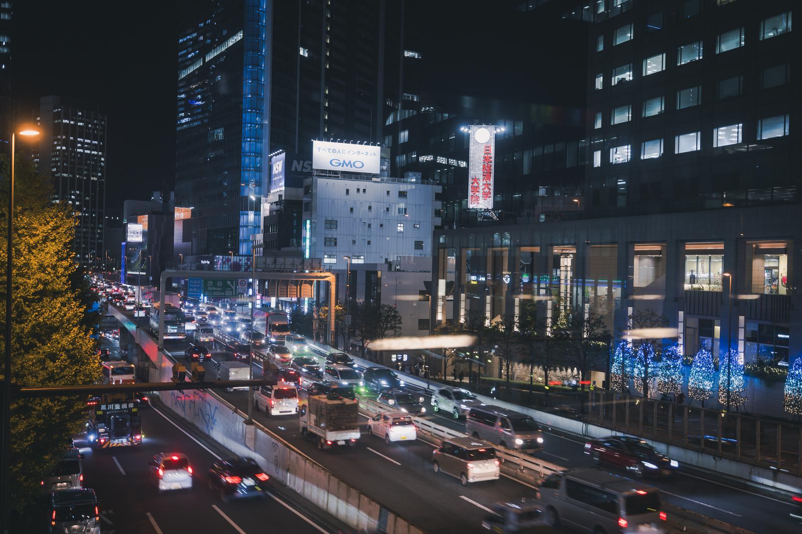 ブリッジ21から見た渋谷の高速道路と夜間の都市夜景。多数の走行車両と高層ビルのネオン看板が照らす夜の都会風景