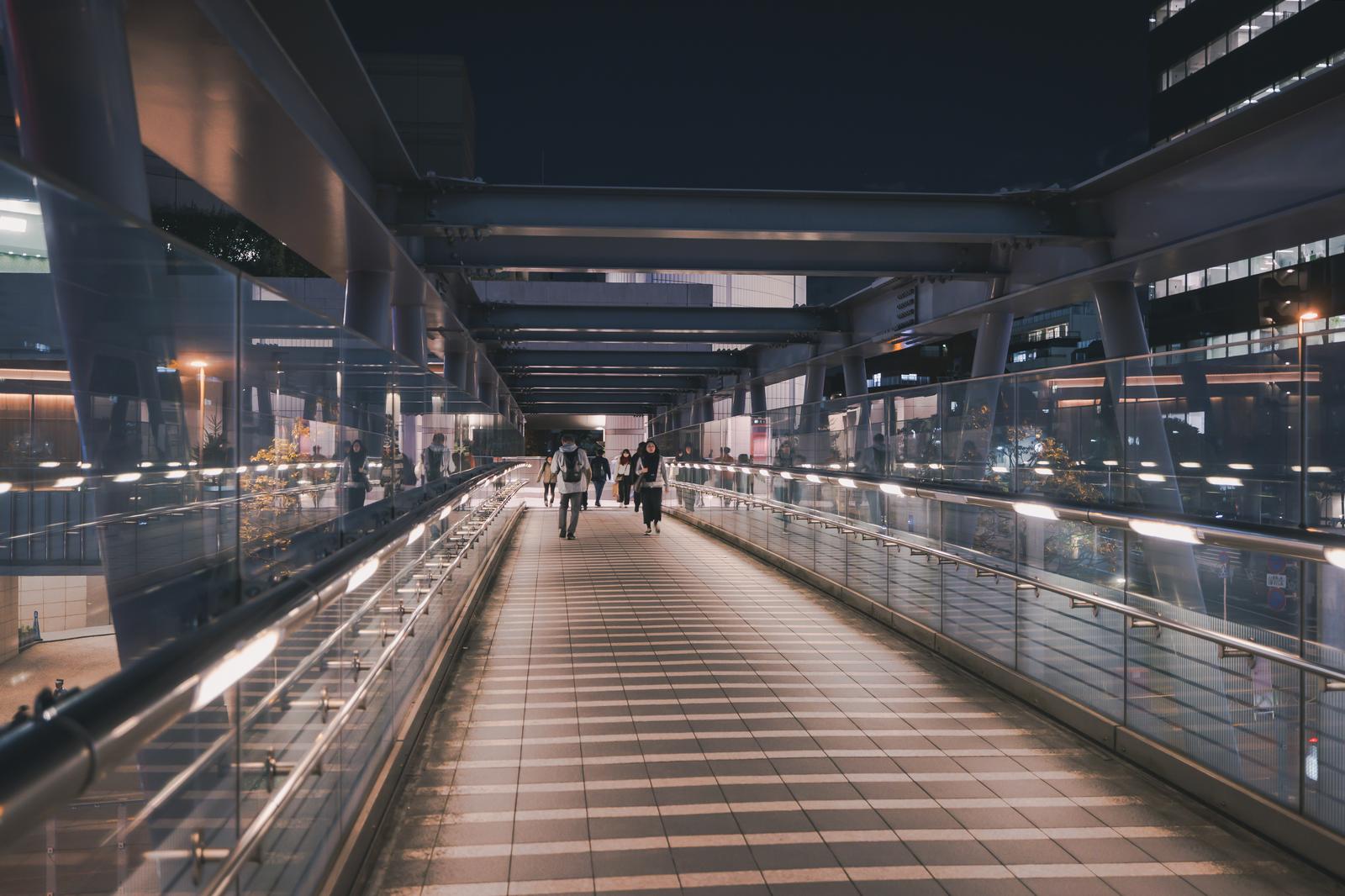 夜間にブリッジ渋谷21通路を歩く複数の人物と周囲のビル