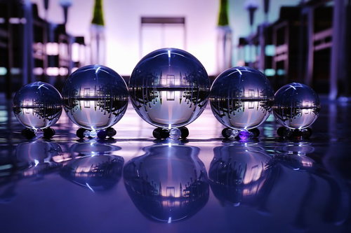 静寂な空間に一列に並ぶ透明な水晶玉とガラス玉の光と影