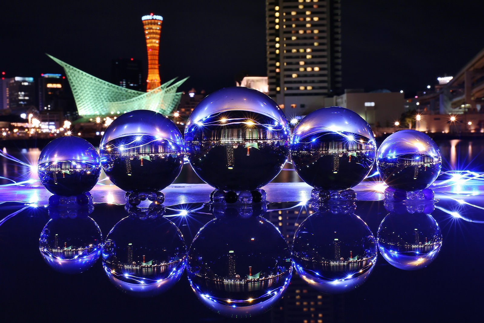 神戸の夜景が映り込んだ透明な水晶玉が水面に浮かんでいる