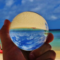 真夏のビーチで手に持つ水晶玉に映る海と青空の写真