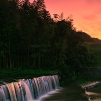 赤く染まる夕刻の空と滝から舞い上がる水しぶきの写真