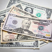 散らばったさまざまな額面のアメリカ紙幣（50ドル、10ドル、1ドル）の写真