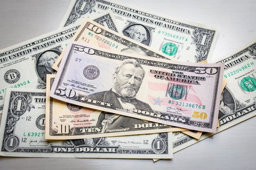 散らばったさまざまな額面のアメリカ紙幣（50ドル、10ドル、1ドル）