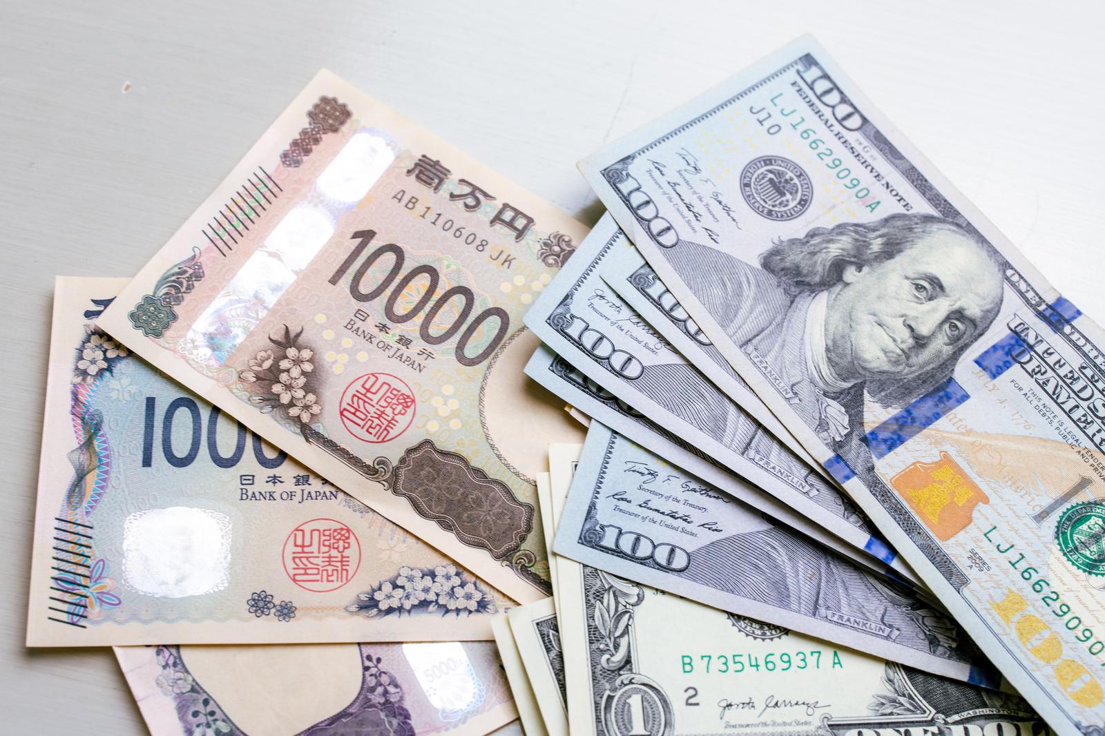 日本円の新紙幣1000円と10000円の上に米ドル紙幣が重ねられた現金