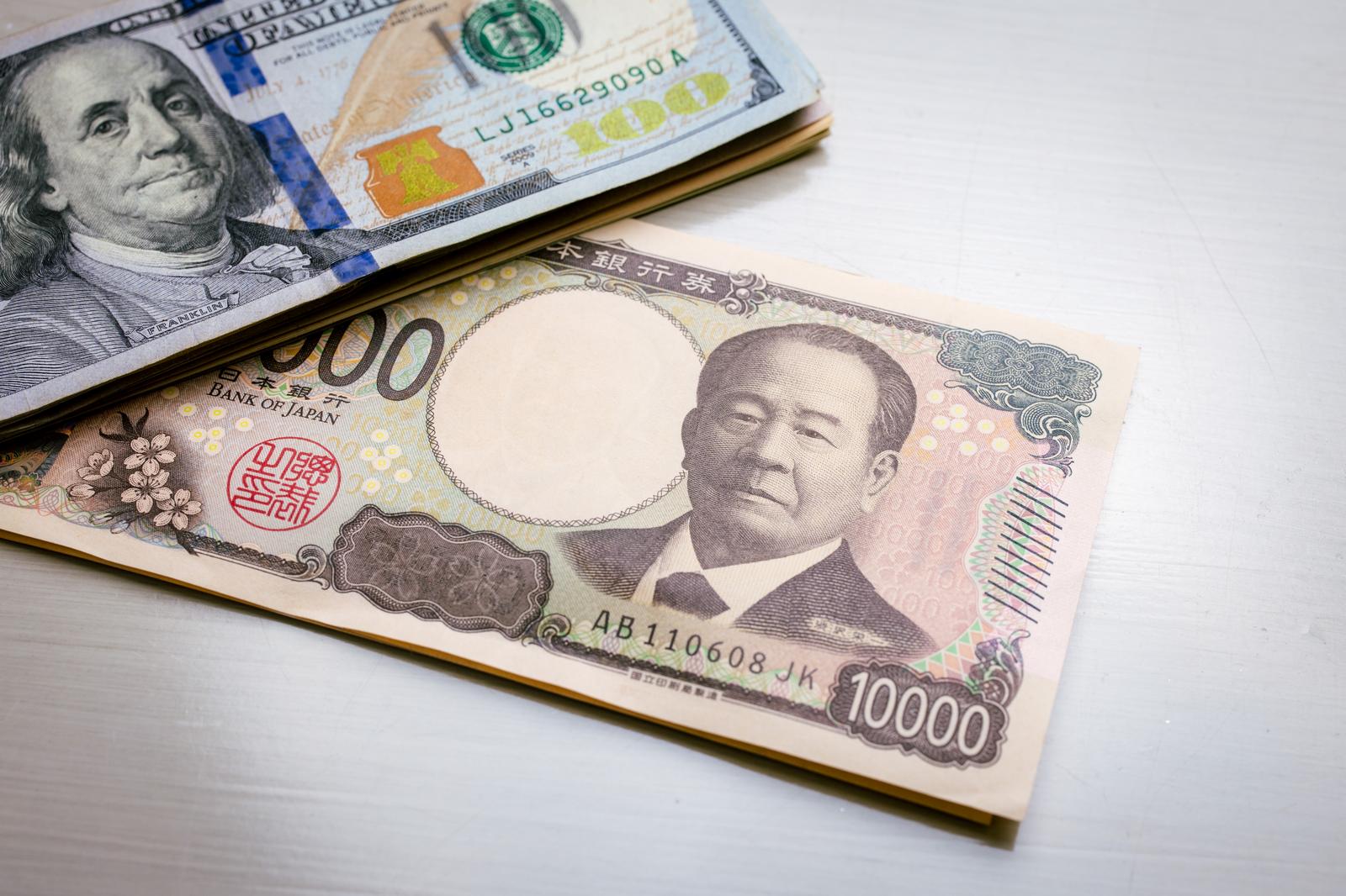 日本の新紙幣10000円と米ドル100ドル紙幣が並んでいる