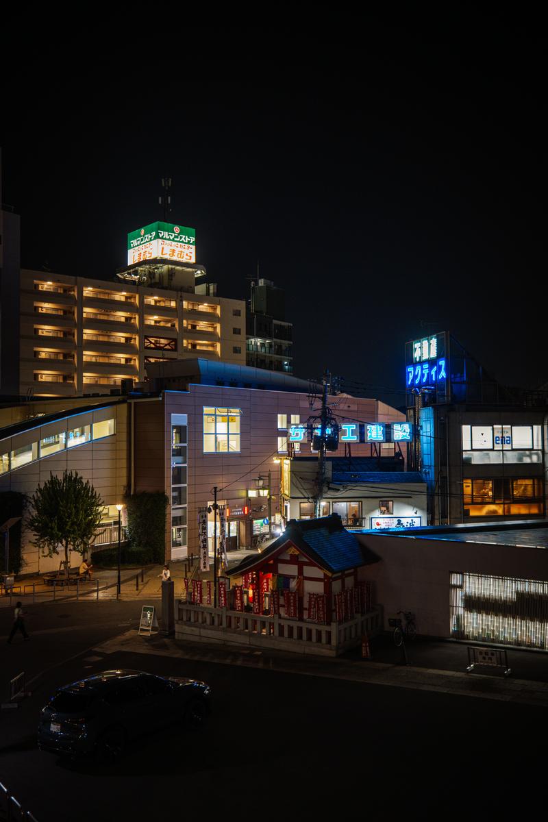 夜の椎名町駅前で赤い鳥居の長崎神社とネオンサインが光る街並み