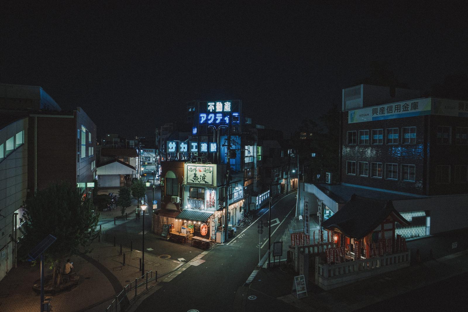 Nighttime shopping district with blue neon lights, viewed from Shiina Bridge in Shiinamachi