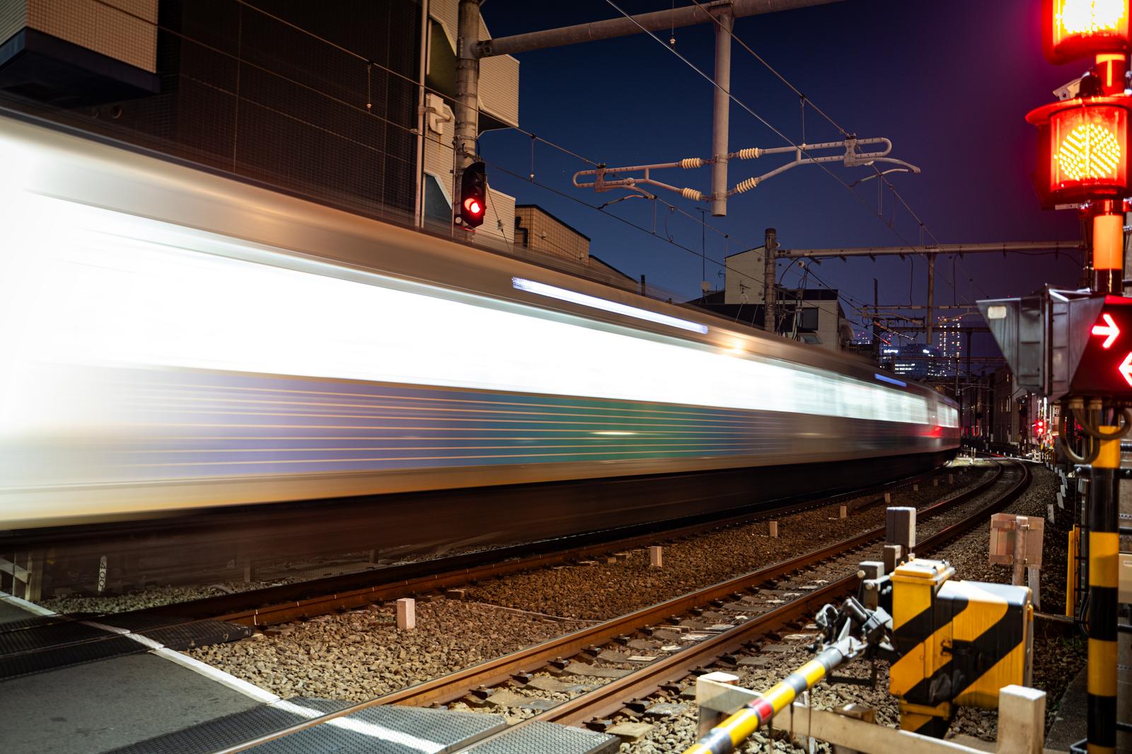 夜の踏切を通過する電車を長時間露光で撮影した流し撮り