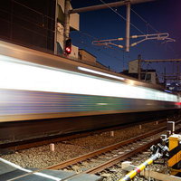 夜間の踏切を高速通過する電車の流し撮りの写真