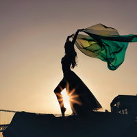 夕日を背に布をはためかせて踊るシルエットダンサーの写真