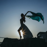 光芒の中でポーズを決めるダンサーのシルエットの写真