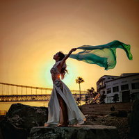 黄金色に染まる空で長い布をなびかせて踊る踊り子の写真