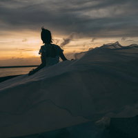 夕焼け空の砂浜でウェディングドレスを着た女性のシルエットの写真