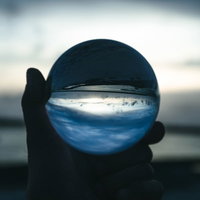 日没の砂浜で手に持つガラス玉と水晶の光景の写真