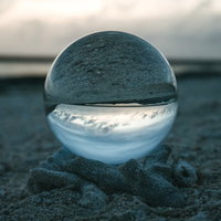 ガラス玉を通して見る砂浜の日没と海の風景の写真