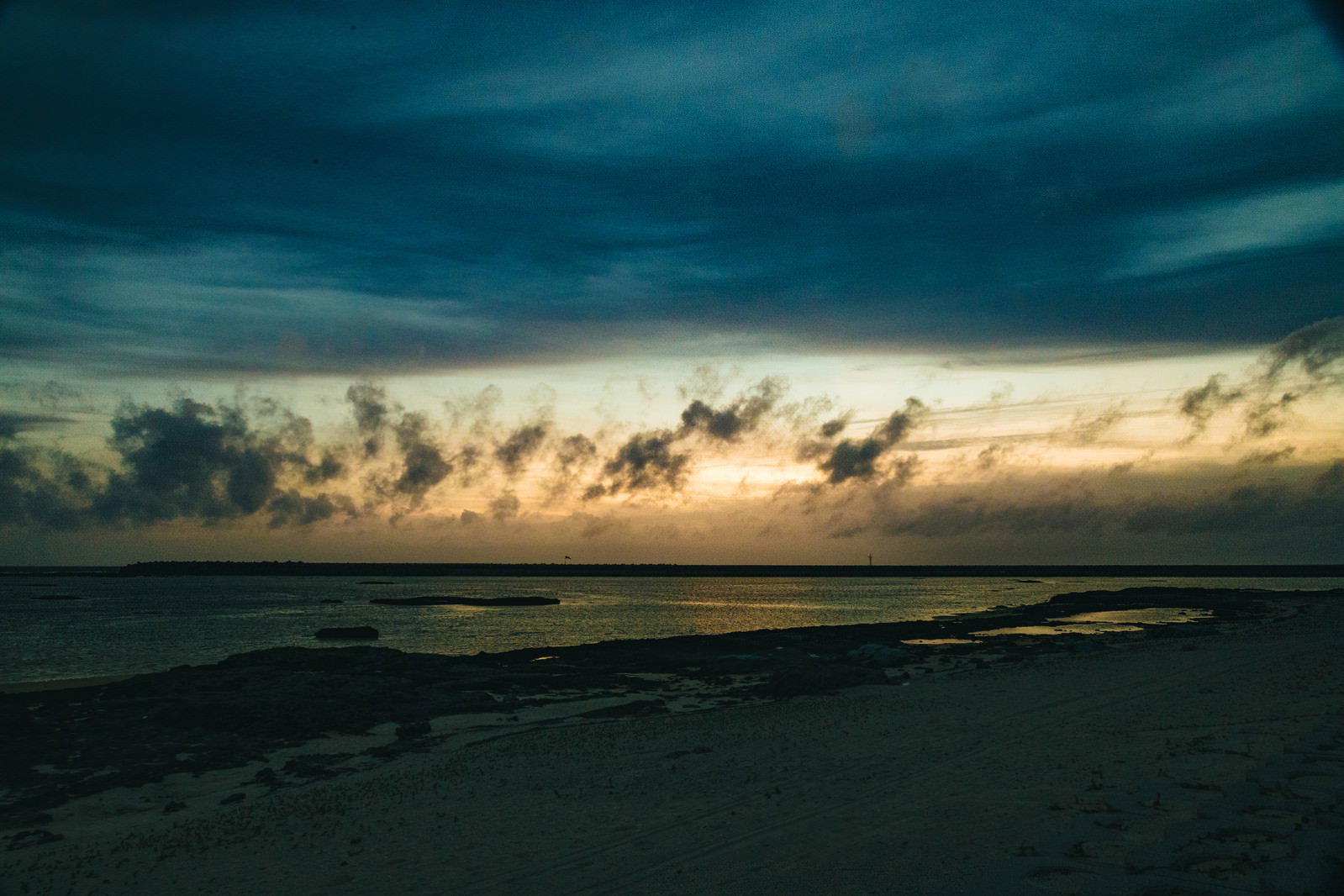 夕日に照らされた海と空、オレンジ色の雲が美しく広がる砂浜の風景