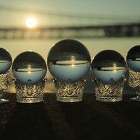 一列に並んだ水晶越しに見る夕日と橋のシルエットの写真