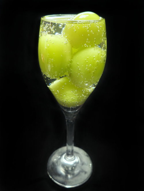 緑色の葡萄入りのシャンパン、透明なワイングラスで見せるアルコール飲料