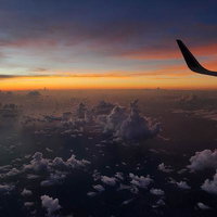 飛行機の窓から眺める雲海に映る夕焼けのサンセットの写真