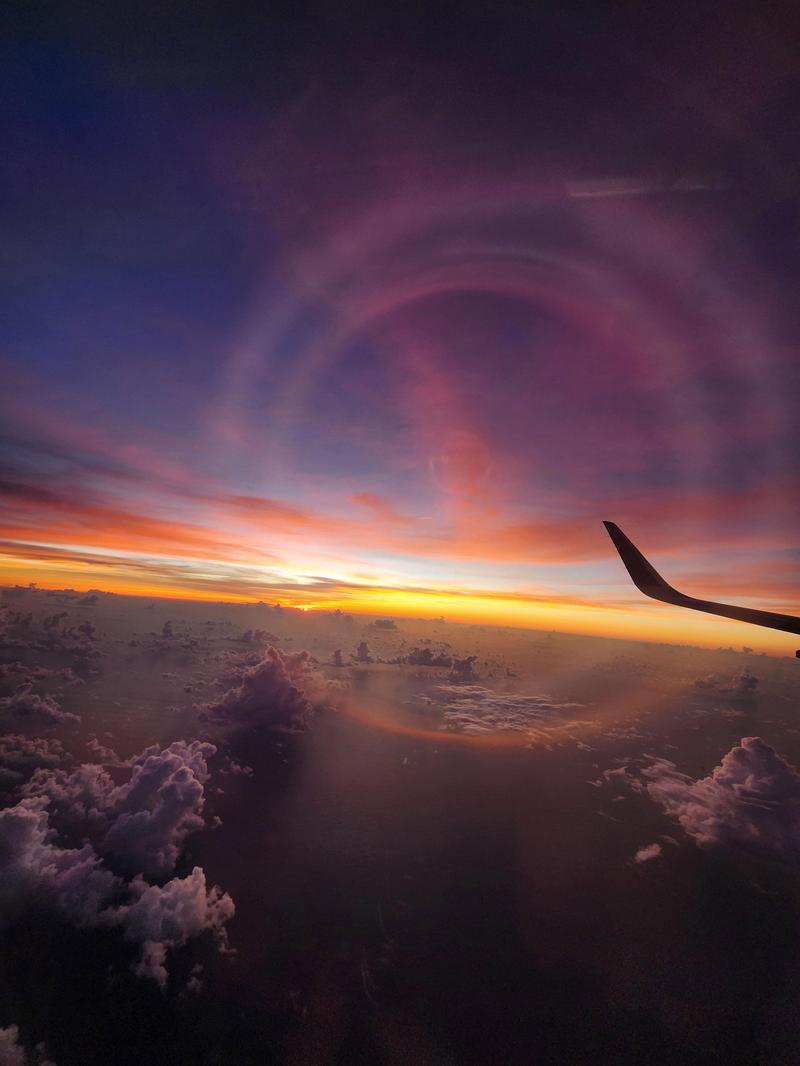 飛行機の翼越しに見える夕焼けの空と雲海