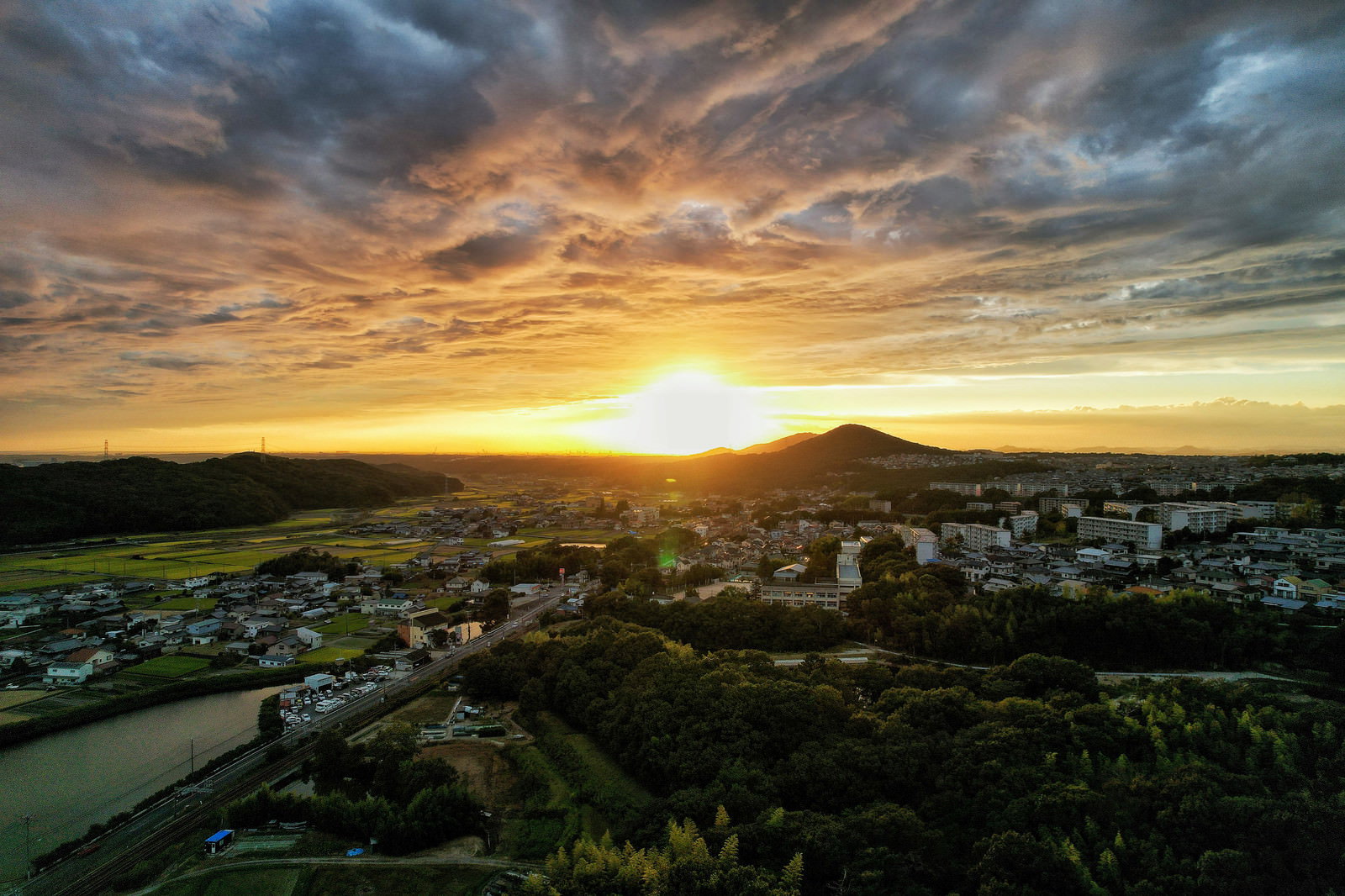 オレンジ色の夕陽が沈む空の下に広がる住宅地の町並み