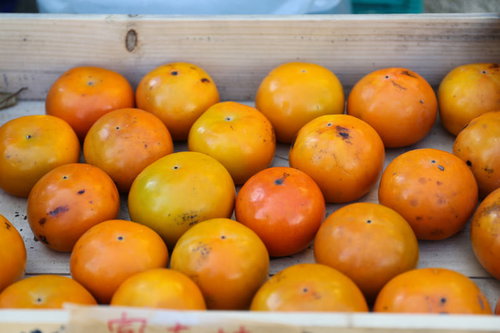 木箱に積み重なった秋の柿 - 新鮮な収穫