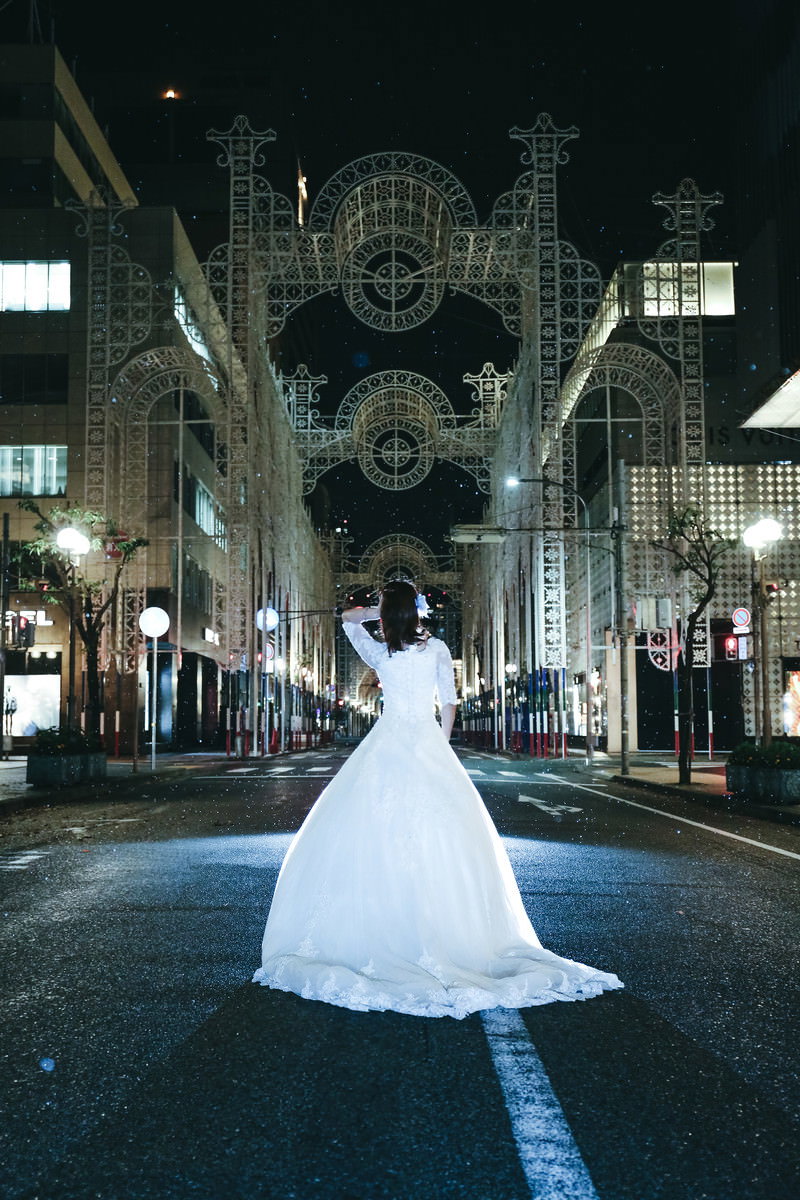 小雨が降る中、点灯前の神戸ルミナリエの前に白いドレスを着た女性が立っている［モデル：モデルリリース］