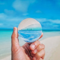 ガラス玉越しに見る南国ビーチの海と砂浜と青空の写真