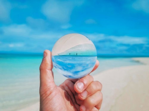 ガラス玉越しに見る南国ビーチの海と砂浜と青空