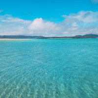 どこまでも続く南国リゾートの透明度の高い海と青空の写真