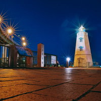 夜の旧堺燈台にさす光芒と夜景、歴史的建造物のライトアップの写真