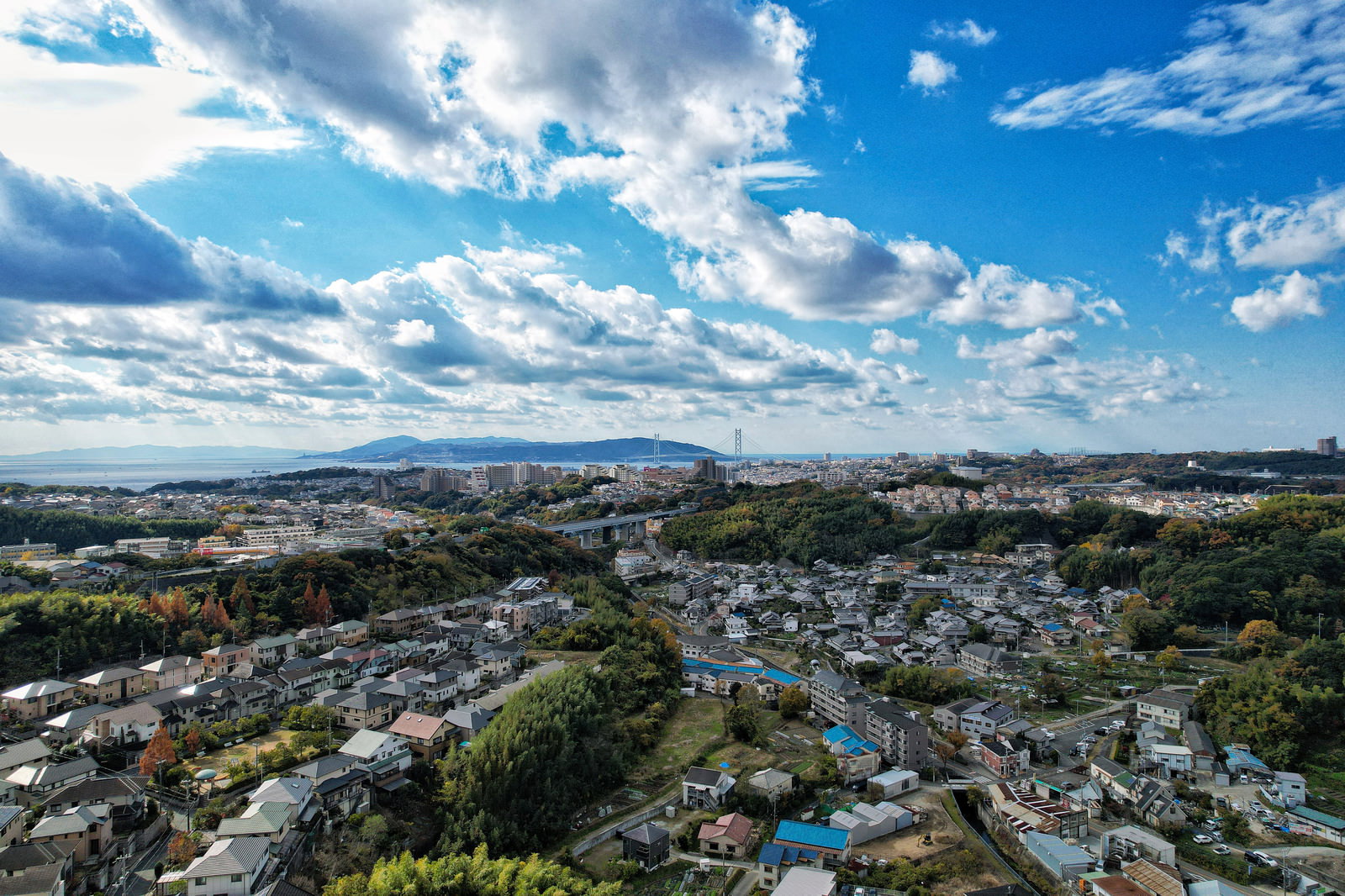 青空と白い雲の下に広がる住宅街の俯瞰風景