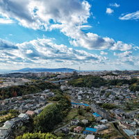 眼下に見渡す住宅街と果てしなく続く青い空の写真