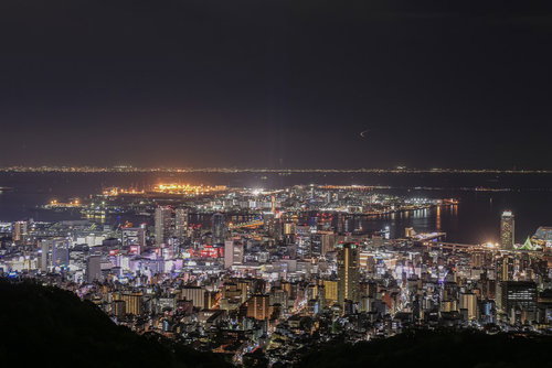遠くに見える都市の夜景と港の灯り、水面に映る夜間の都市風景