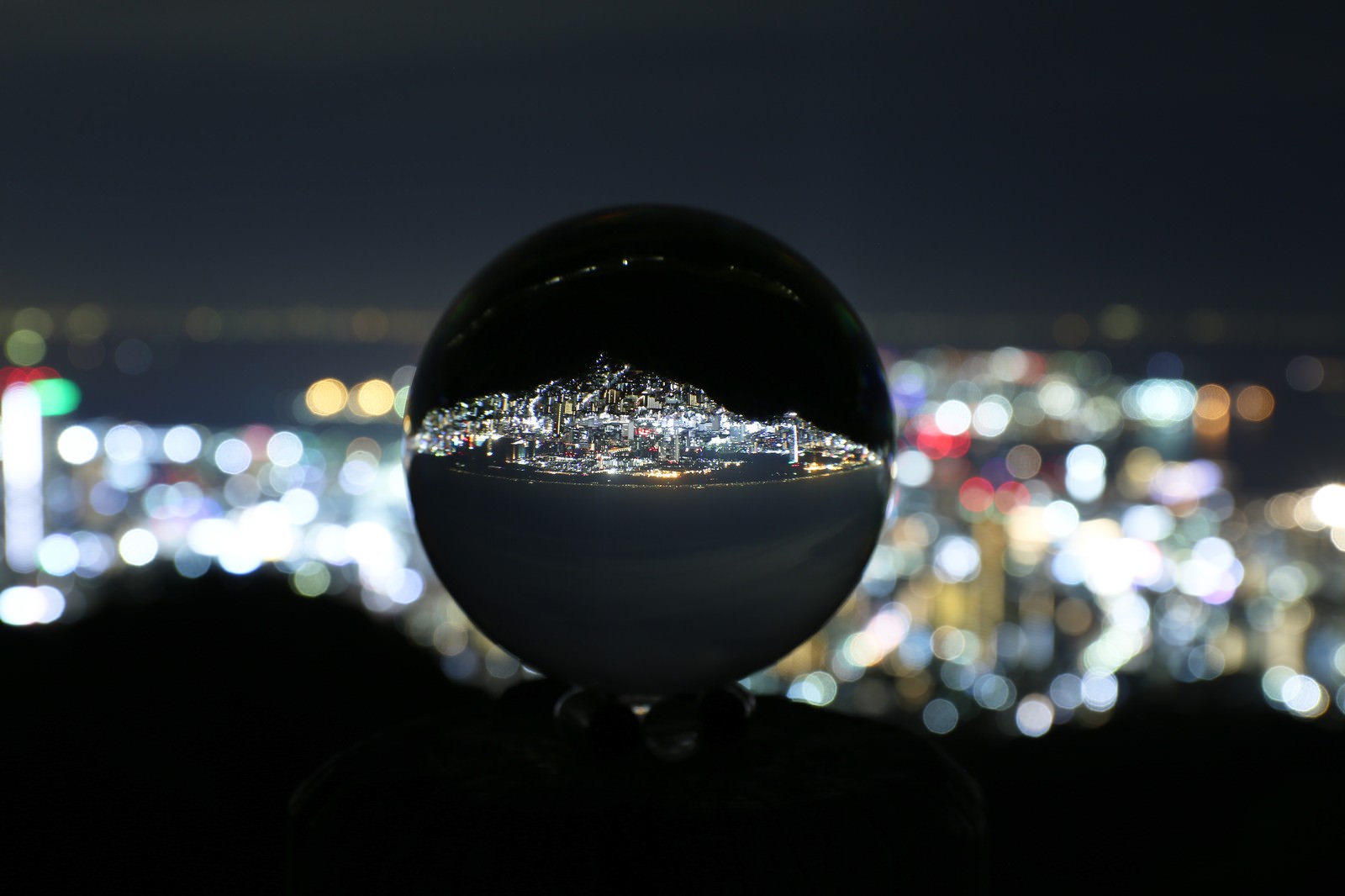 透明なガラス玉に反転した夜景が映り込み背景に光のボケが広がる