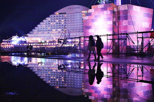 雨上がりの水溜りに映る神戸メリケンパークオリエンタルホテルとカップル